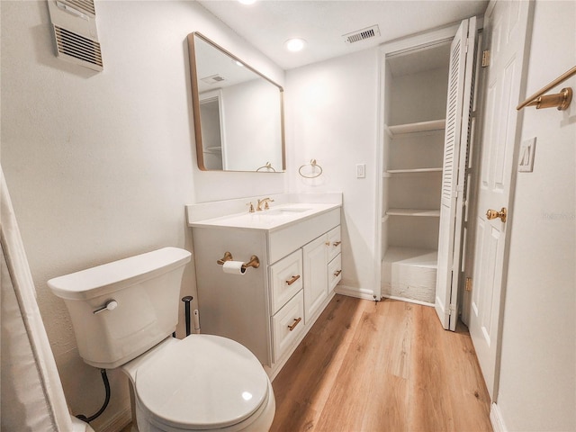 bathroom featuring toilet, wood finished floors, visible vents, vanity, and baseboards