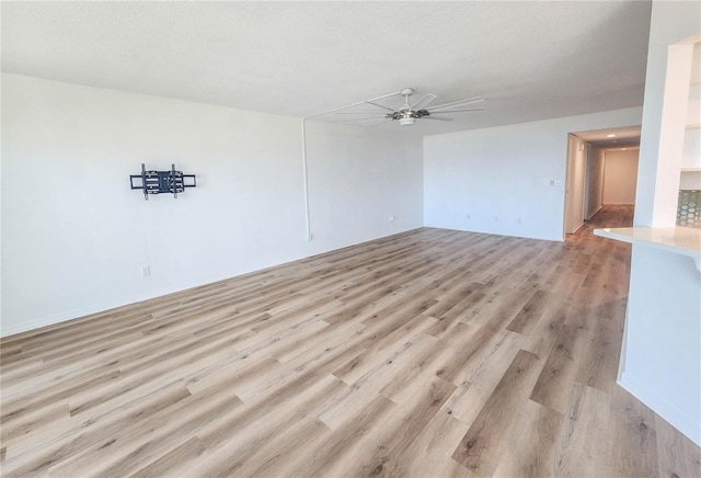 spare room featuring a ceiling fan, light wood-style flooring, and a textured ceiling