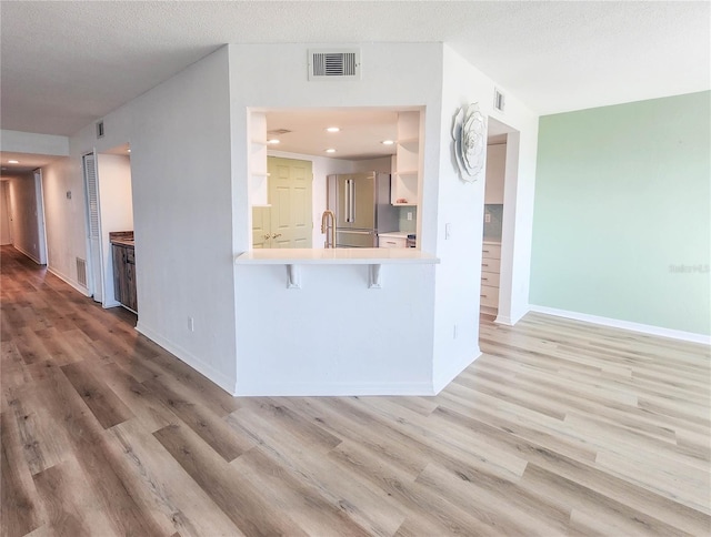 kitchen featuring light wood-style floors, baseboards, high quality fridge, and visible vents