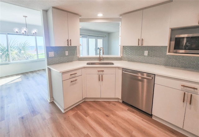 kitchen with light countertops, a sink, light wood finished floors, and stainless steel dishwasher