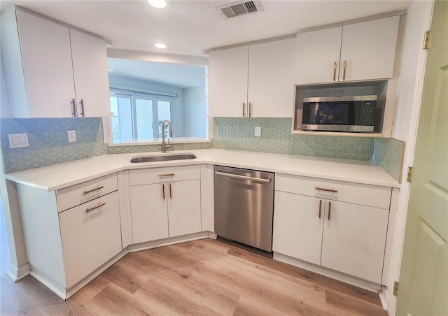 kitchen with visible vents, stainless steel appliances, light countertops, light wood-type flooring, and a sink