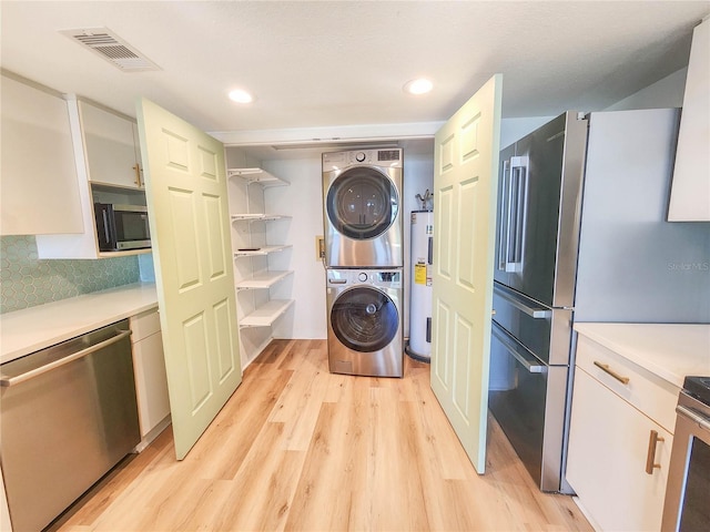 laundry room featuring visible vents, light wood-style floors, electric water heater, stacked washing maching and dryer, and recessed lighting