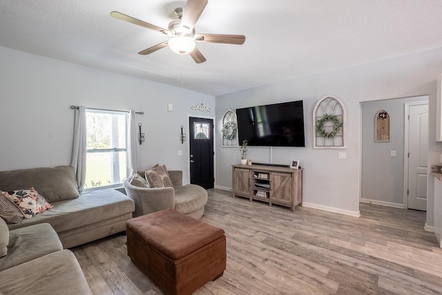 living room featuring light wood-style floors, baseboards, and a ceiling fan