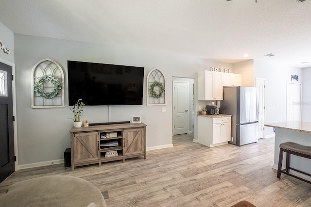 living area featuring light wood-style flooring, baseboards, and a textured ceiling