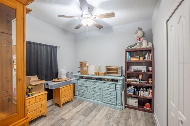 office space featuring light wood-style floors, a textured ceiling, and a ceiling fan