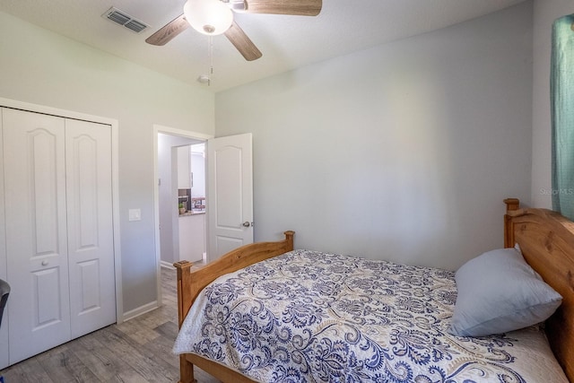 bedroom with a closet, visible vents, ceiling fan, and wood finished floors