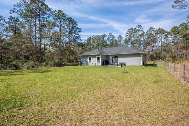 rear view of house featuring fence and a yard