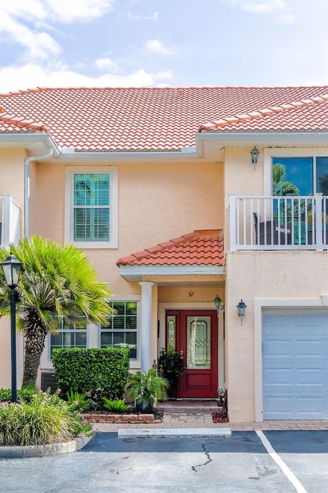 doorway to property featuring a tile roof, a balcony, and stucco siding