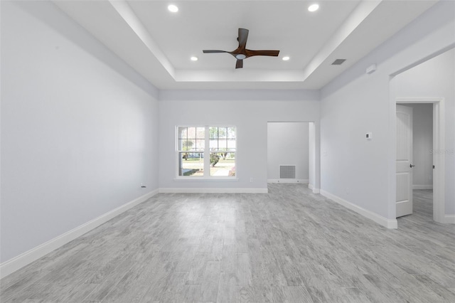 unfurnished living room featuring recessed lighting, visible vents, baseboards, light wood-type flooring, and a raised ceiling