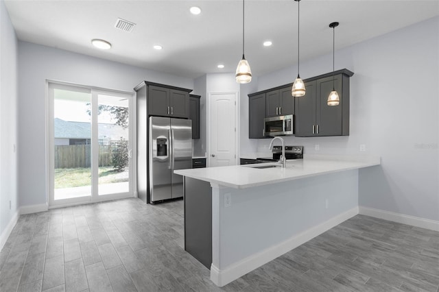 kitchen featuring visible vents, appliances with stainless steel finishes, wood finished floors, a peninsula, and light countertops