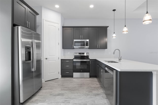 kitchen with recessed lighting, light countertops, appliances with stainless steel finishes, a sink, and a peninsula