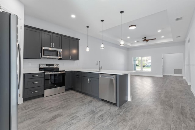 kitchen featuring a peninsula, a sink, visible vents, appliances with stainless steel finishes, and a raised ceiling