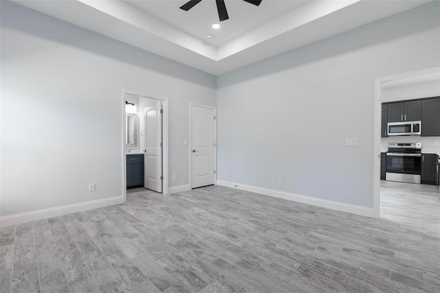 unfurnished room featuring baseboards, ceiling fan, a tray ceiling, light wood-type flooring, and recessed lighting