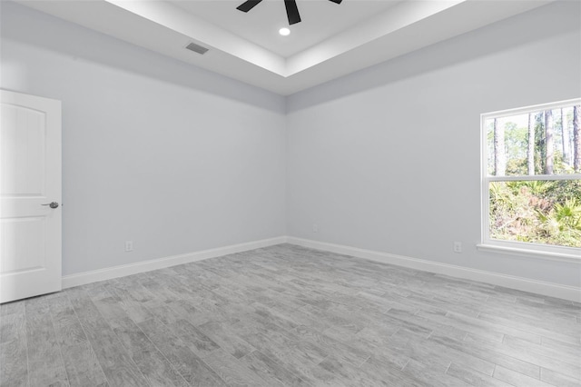 unfurnished room featuring light wood-type flooring, a healthy amount of sunlight, visible vents, and baseboards