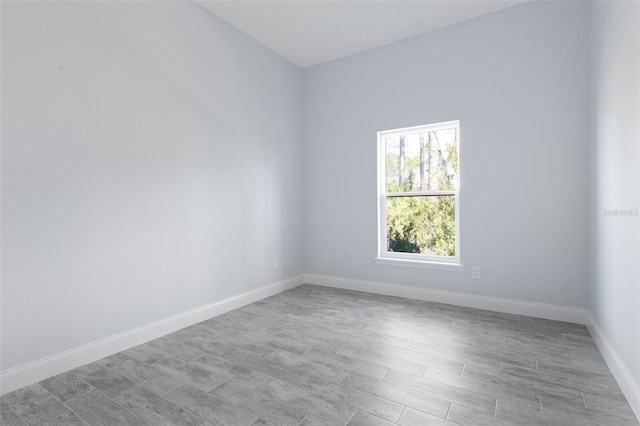 spare room featuring baseboards and wood finished floors