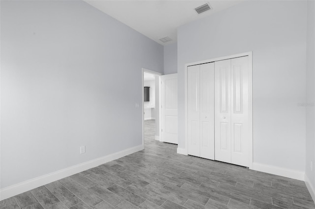 unfurnished bedroom featuring a closet, visible vents, baseboards, and wood finished floors