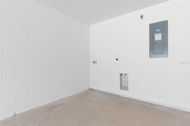 spare room with concrete block wall, electric panel, and concrete flooring