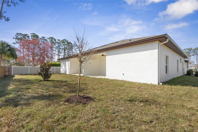 exterior space featuring stucco siding, a fenced backyard, and a yard