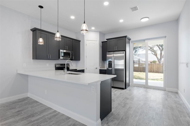 kitchen featuring visible vents, appliances with stainless steel finishes, a peninsula, light countertops, and a sink