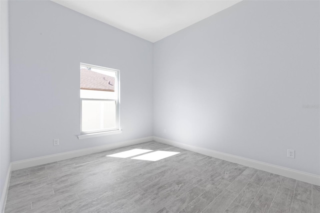 unfurnished room with baseboards and wood finished floors