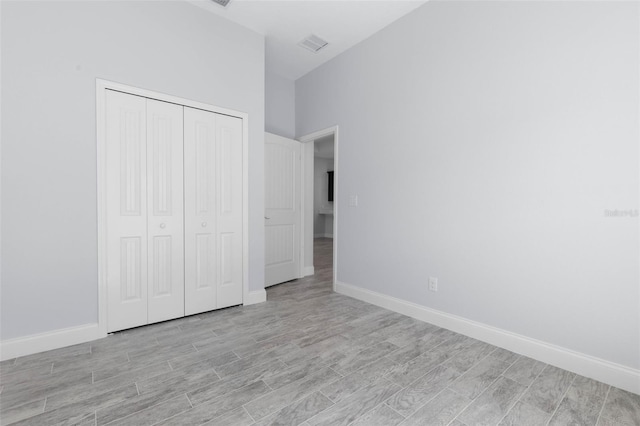 unfurnished bedroom featuring light wood-style flooring, a closet, visible vents, and baseboards