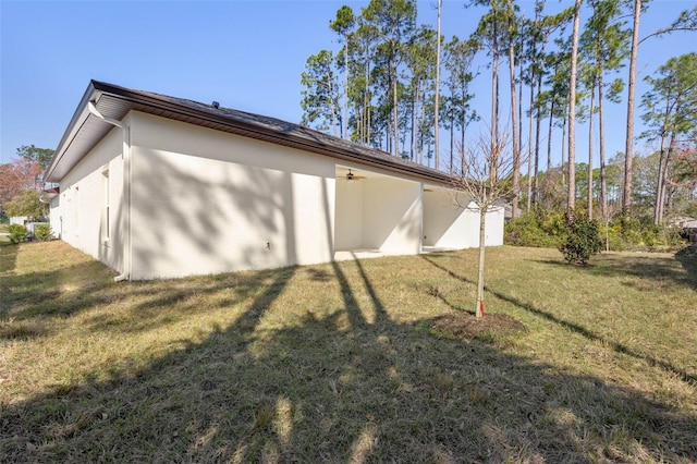 back of property with a yard and stucco siding