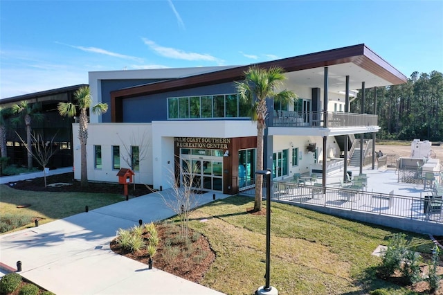 view of front of property with a patio area, a front yard, stairway, and stucco siding