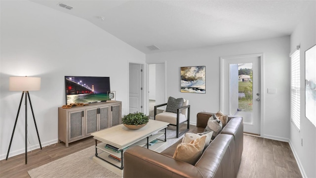 living area featuring baseboards, visible vents, vaulted ceiling, and wood finished floors