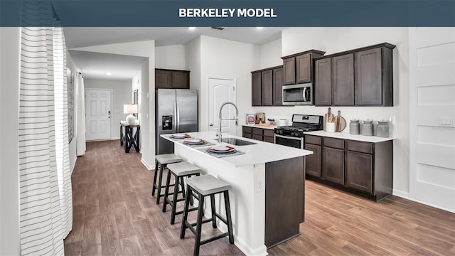 kitchen with appliances with stainless steel finishes, a breakfast bar area, a sink, and light wood-style flooring