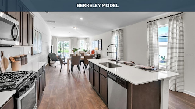 kitchen featuring stainless steel appliances, wood finished floors, visible vents, a sink, and light countertops