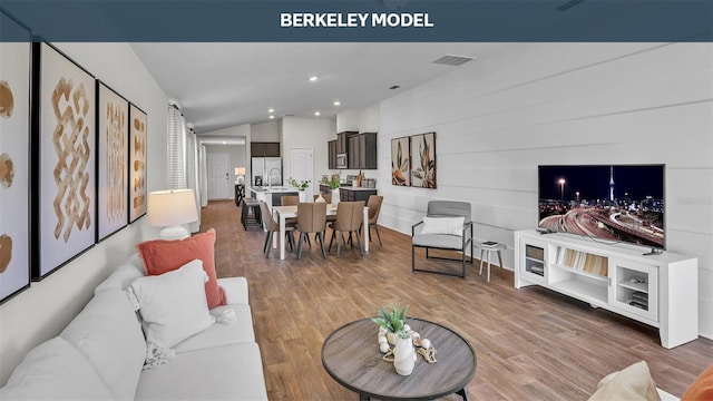 living room featuring lofted ceiling, visible vents, wood finished floors, and recessed lighting