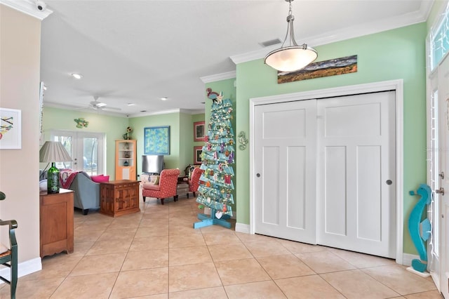 foyer with visible vents, crown molding, light tile patterned floors, baseboards, and ceiling fan