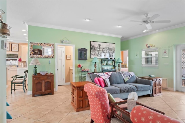 living area with light tile patterned flooring, a ceiling fan, baseboards, and ornamental molding