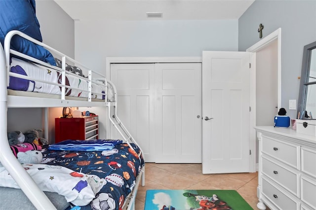 bedroom featuring light tile patterned floors, visible vents, and a closet