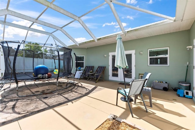 view of patio featuring a trampoline, a lanai, and fence