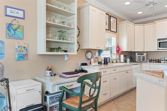 kitchen with light tile patterned floors, a sink, light countertops, crown molding, and stainless steel microwave