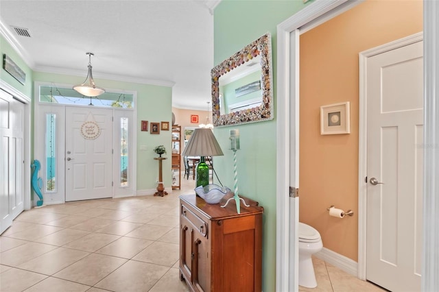 foyer with light tile patterned floors, baseboards, visible vents, and ornamental molding