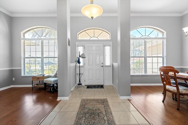 entryway with plenty of natural light, light wood-style flooring, and crown molding