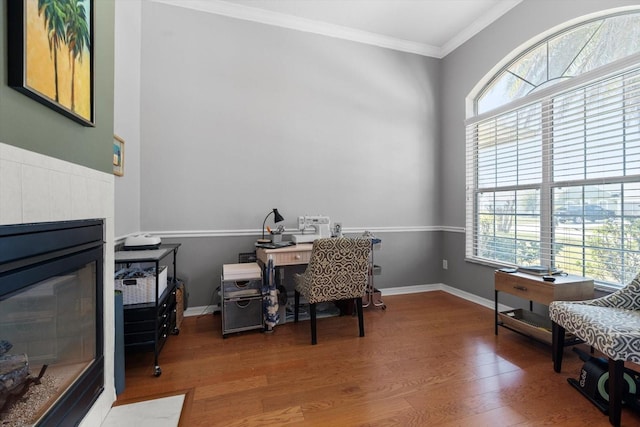 office space with baseboards, a fireplace, wood finished floors, and crown molding