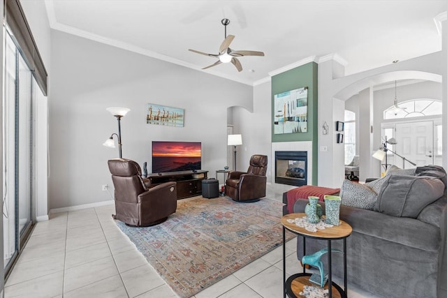 living room featuring arched walkways, light tile patterned floors, a tiled fireplace, and crown molding