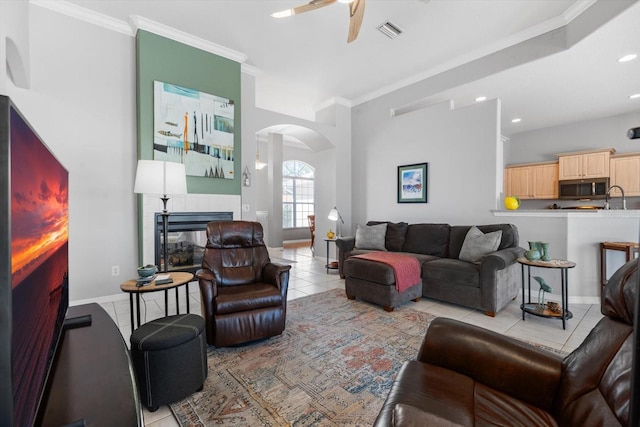 living area featuring arched walkways, visible vents, crown molding, and a fireplace