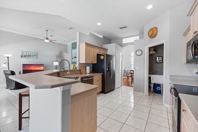 kitchen featuring electric range, visible vents, a breakfast bar, refrigerator with ice dispenser, and a sink