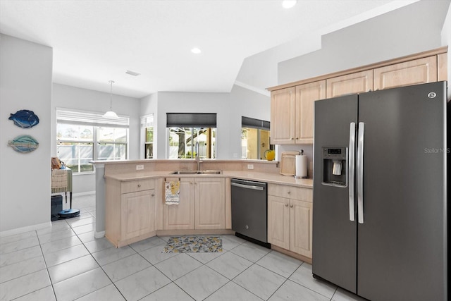 kitchen featuring appliances with stainless steel finishes, a peninsula, light countertops, light brown cabinetry, and a sink