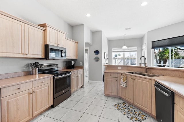 kitchen featuring a sink, light countertops, appliances with stainless steel finishes, and light brown cabinets