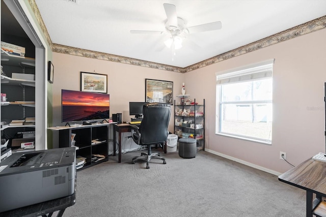 carpeted office space featuring ceiling fan and baseboards