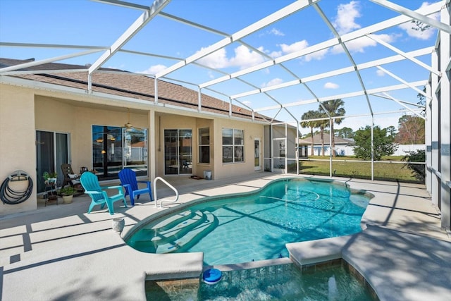 view of pool with ceiling fan, a patio, a pool with connected hot tub, and glass enclosure