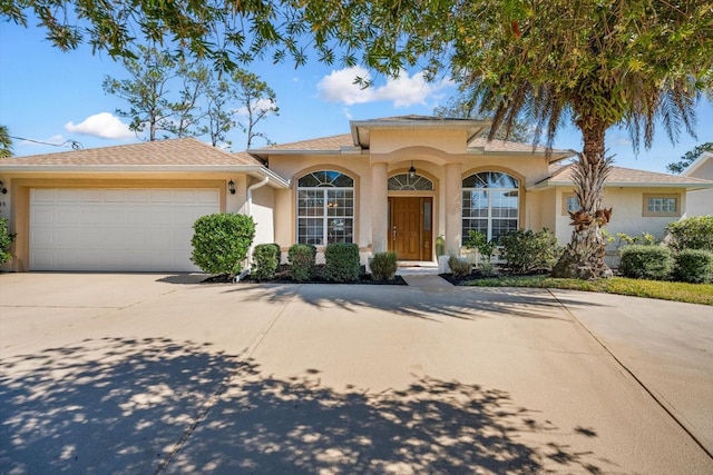 mediterranean / spanish-style house featuring concrete driveway, an attached garage, and stucco siding