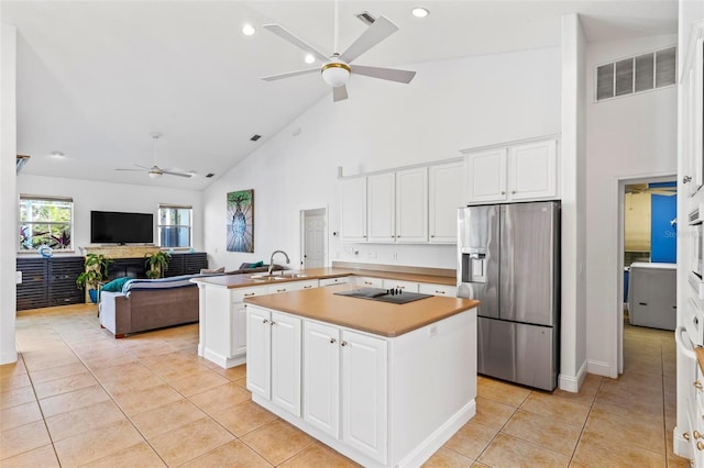 kitchen with a center island, stainless steel refrigerator with ice dispenser, a sink, a peninsula, and black electric cooktop