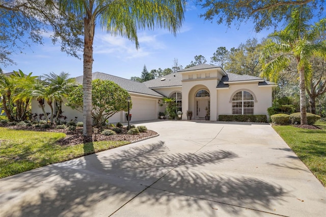 mediterranean / spanish house with a garage, driveway, and stucco siding