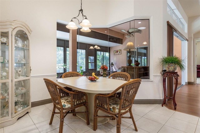 dining room featuring tile patterned flooring, baseboards, a high ceiling, and an inviting chandelier